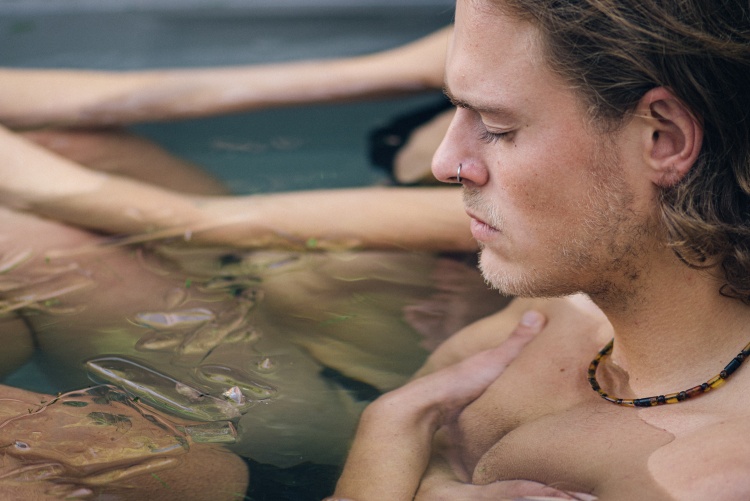 Mann mit geschlossenen Augen badet in kaltem Wasser zwischen Eiswürfeln. Wim-Hof-Methode, Kältetherapie, Atemtechniken, Yoga und Meditation