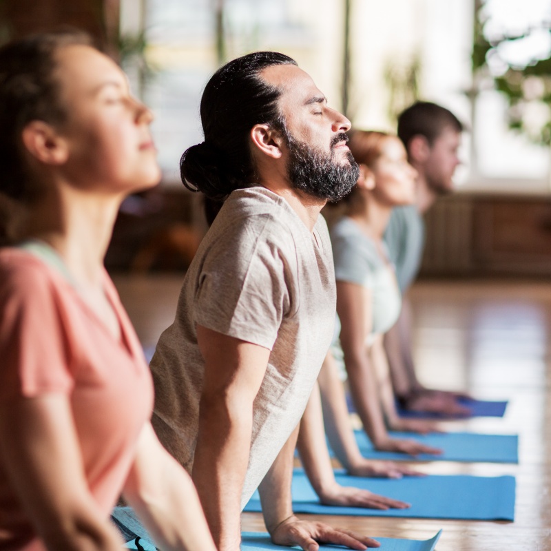 Gruppe von Menschen, die im Studio die Yoga-Hundepose machen