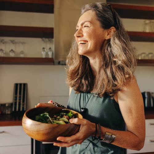 Frau lächelt glücklich, während sie eine Buddha-Schüssel hält